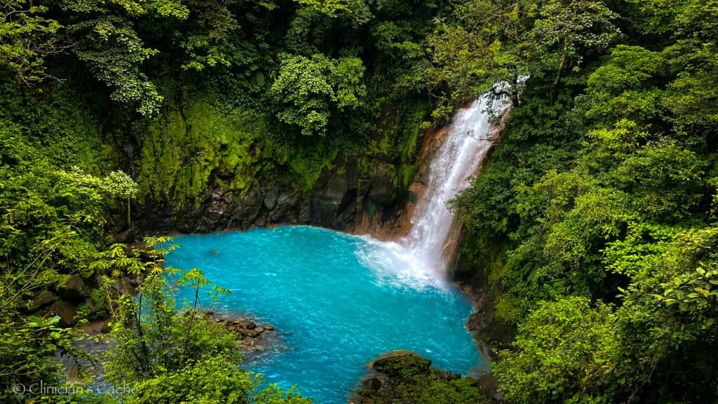 Rio Celeste waterfall in Tenorio Volcano National Park, Costa Rica, cascading into a vibrant turquoise pool surrounded by lush green rainforest.