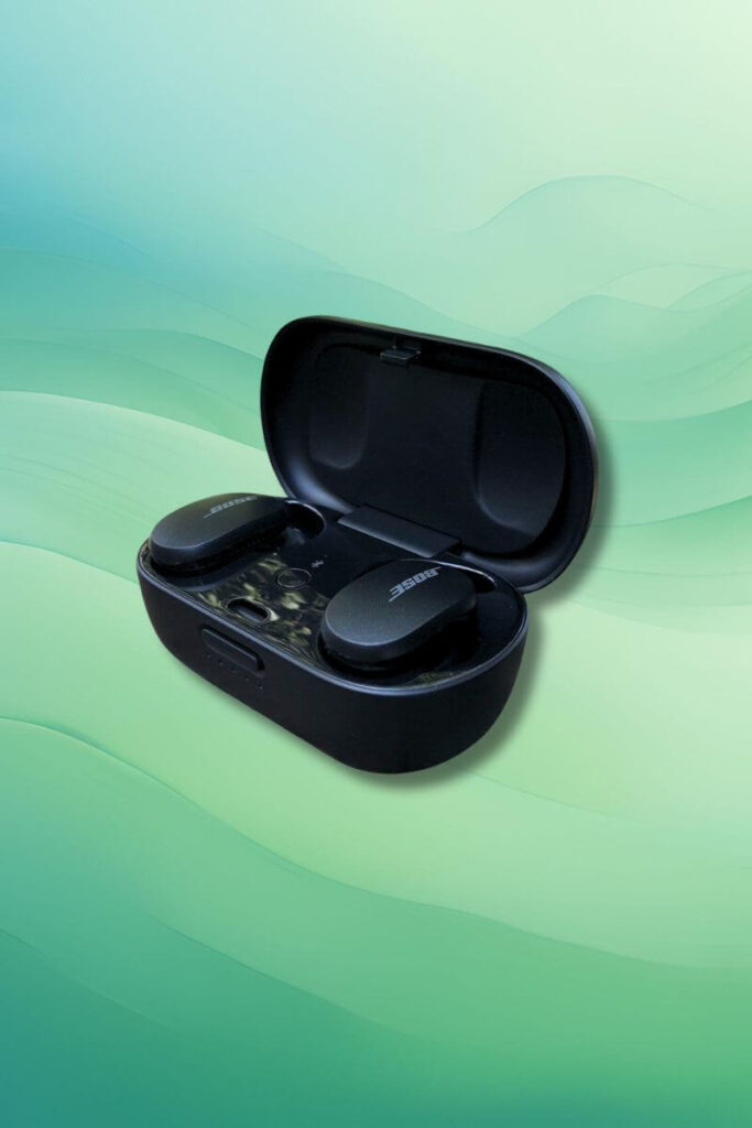 A close-up of the Bose QuietComfort earbuds resting securely inside their open black charging case, displayed against a soft green gradient background.