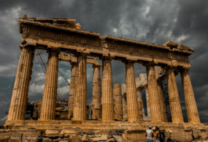 A dramatic view of the Parthenon in Athens, Greece, under a stormy sky, showcasing the iconic ancient columns and architectural details. The scene captures the awe-inspiring grandeur of the historic ruins, with two visitors in the foreground admiring the site. A crane in the background highlights ongoing preservation efforts, adding context to the timeless significance of this UNESCO World Heritage site. Ideal for an ADHD travel guide to Rome and Athens, emphasizing rich history and breathtaking landmarks