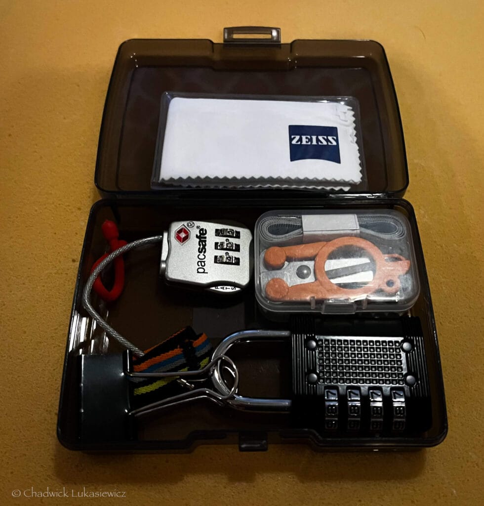 Compact clear gear case containing TSA-approved locks, earplugs, and cleaning cloth for ADHD travel organization.