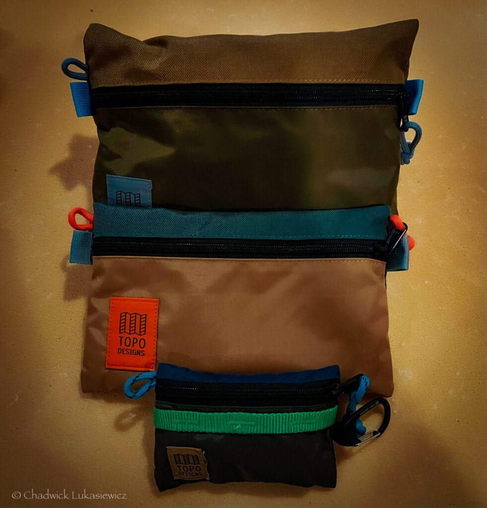 Set of three Topo Designs accessory bags in green, khaki, and tan, organized by size and color for ADHD travel packing.