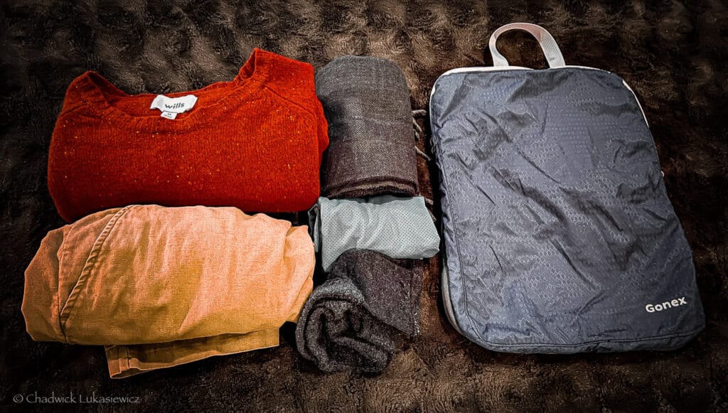 “A set of rolled outfits and a Gonex compression cube, showcasing the outfit rolling method for ADHD-friendly travel.