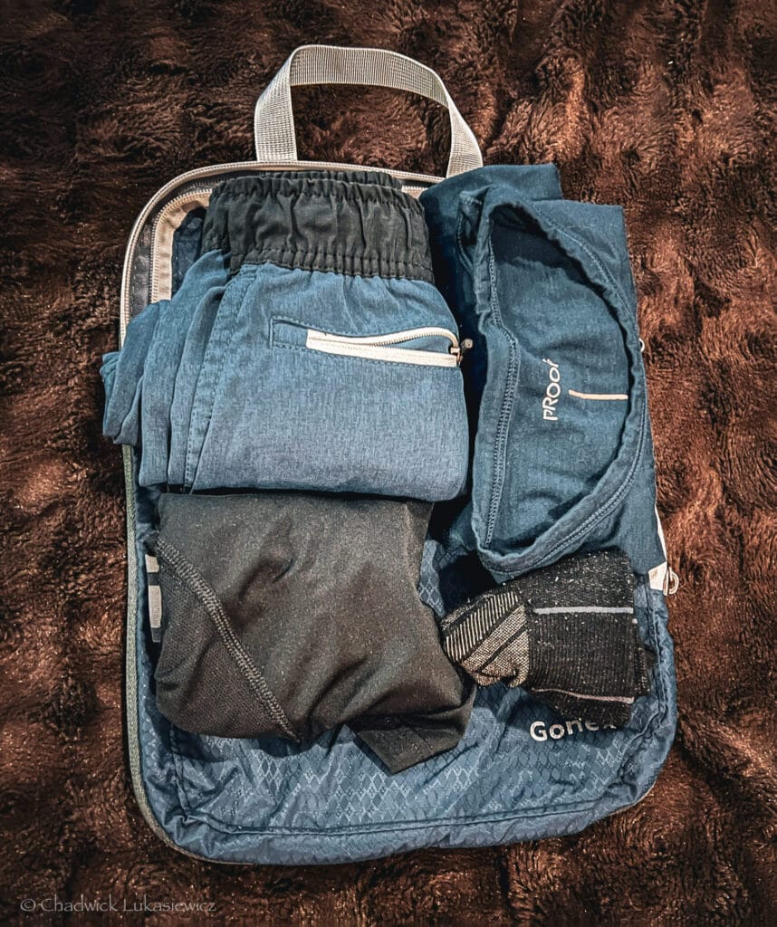 A Gonex compression cube packed with blue and black clothing, using the capsule packing system for ADHD travel organization.
