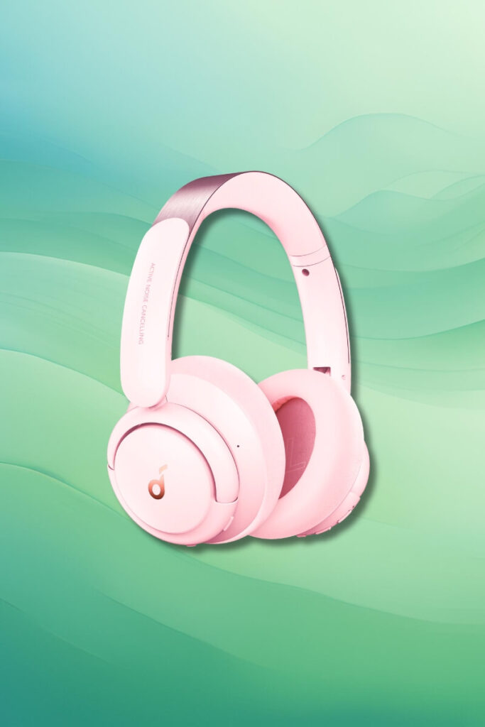 A pair of Soundcore Life Q30 over-ear headphones in pastel pink with rose gold accents, set against a green gradient background. The headphones have cushioned ear cups and an adjustable headband, showcasing their soft color and modern look