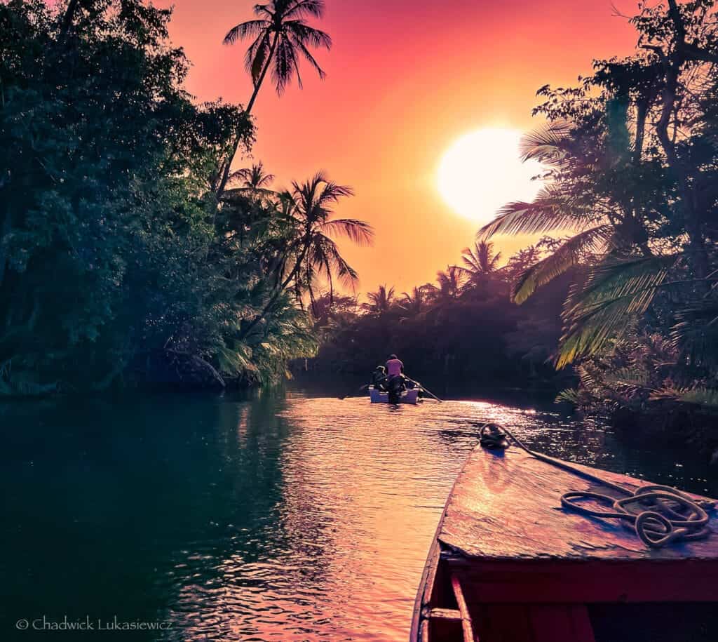 A wooden boat navigating the Indian River in Dominica at sunset, showcasing ADHD travel photography’s focus on light and movement.